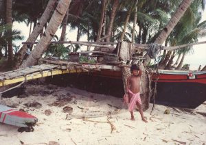 A boy on a beach next to a canoe: He may someday be a star-path navigator.